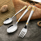 Stylish silverware with golden chevron handles placed on textured burlap and stone surface background.