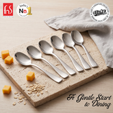 Chef Vicky Ratnani Nexa six-piece baby spoon set with mirror finish, arranged beside baby food on a dining board.
