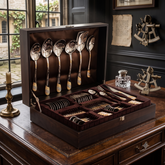 FnS Imperio Gold Plated 90-piece cutlery set displayed in an open wooden box on a luxurious vintage-style dining table.