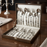 FnS Madrid 18-piece hammered finish cutlery set displayed in an open leatherette box on an elegant dining table.