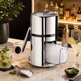 Montavo Ice Crusher with stainless steel body, clear ice tray and scoop displayed on a premium bar counter with cocktails.