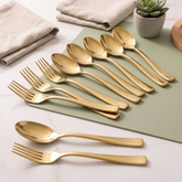 Montavo by FnS Alexa Gold 12 Pc stainless steel cutlery set with polished spoons and forks arranged on a dining table.