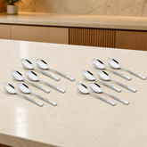 Montavo by FnS Creta 12-piece dessert spoon set displayed on a premium beige kitchen countertop with soft warm lighting.