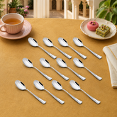 Montavo by FnS Creta 12-piece stainless steel tea spoon set arranged with tea and Indian sweets on a mustard dining table.