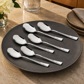 Montavo by FnS Creta 6-piece stainless steel dinner spoon set displayed on a charcoal plate on an elegant dining table.