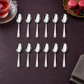 Montavo by FnS Divine 12-piece stainless steel tea spoon set arranged with rose tea, macarons and berries on a plum table.