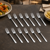 Montavo by FnS Divine 12-piece stainless steel dinner fork set arranged with roasted vegetables and pasta on dining table.