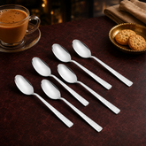 Montavo by FnS Helios 6-piece stainless steel tea spoon set with textured handles arranged beside masala tea and biscuits.