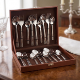 Montavo by FnS Lush 18 Pc laser engraved cutlery set arranged in an open leatherette box on an elegant wood dining table.