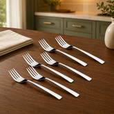 Montavo by FnS Trendz 6-piece dinner fork set in polished silver, arranged on a walnut dining table in a modern kitchen.