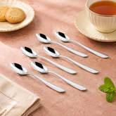 Montavo by FnS Verona 6-piece stainless steel tea spoon set arranged beside a cup of tea, biscuits and fresh mint leaves.
