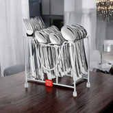Large stainless steel cutlery set with modern handles displayed in metal stand on dining table.