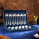 Premium silver cutlery set in a blue velvet box, placed on festive table with lights and stars.