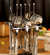 Elegant stainless steel cutlery set with etched handles neatly displayed in a modern vertical stand.