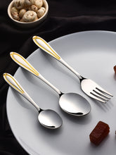 Three polished Stainlessss steel utensils with gold-plated handles resting on white plate with mushrooms and date beside them