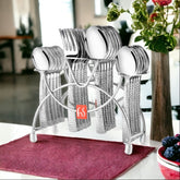 Textured-handle cutlery set neatly arranged in a chrome stand, placed on a dining table with flowers.