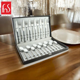 Elegant boxed Stainlessss steel cutlery set with patterned handles displayed on a wooden dining table.