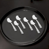 FNS Zest 6-piece baby spoon set with textured handles elegantly arranged on black serving tray, showcasing mirror finish and premium Stainlessss steel quality.