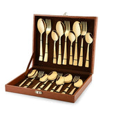 Luxurious gold cutlery set neatly arranged in a brown presentation box with organized interior slots.