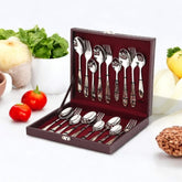 Decorative cutlery set in maroon velvet case surrounded by fresh vegetables on a white kitchen counter.