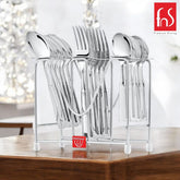 Complete stainless-steel cutlery set in metal stand placed on wooden surface with soft background lighting.