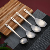 Montavo Amazon 4-piece Stainlessss steel serving spoons on striped wooden board with black placemat, showcasing mirror polish finish and ergonomic design.