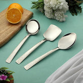 Montavo by FNS Pebble 3-piece serving set with laser engraved handles displayed on turquoise table with flowers and oranges