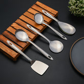 Montavo Trinity Stainlessss steel serving spoons set of 5 displayed on wooden trivet with decorative plant on dark background