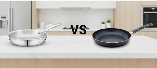 Comparison image showing a stainless steel triply frypan on the left and a black nonstick frypan on the right, placed on a kitchen counter with ‘VS’ text in the middle, representing a comparison between the two cookware types.