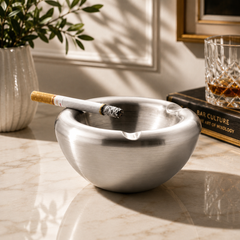 FnS Oxford stainless steel ash tray with smooth rounded edges, shown on a marble bar counter with cigarette and drink.
