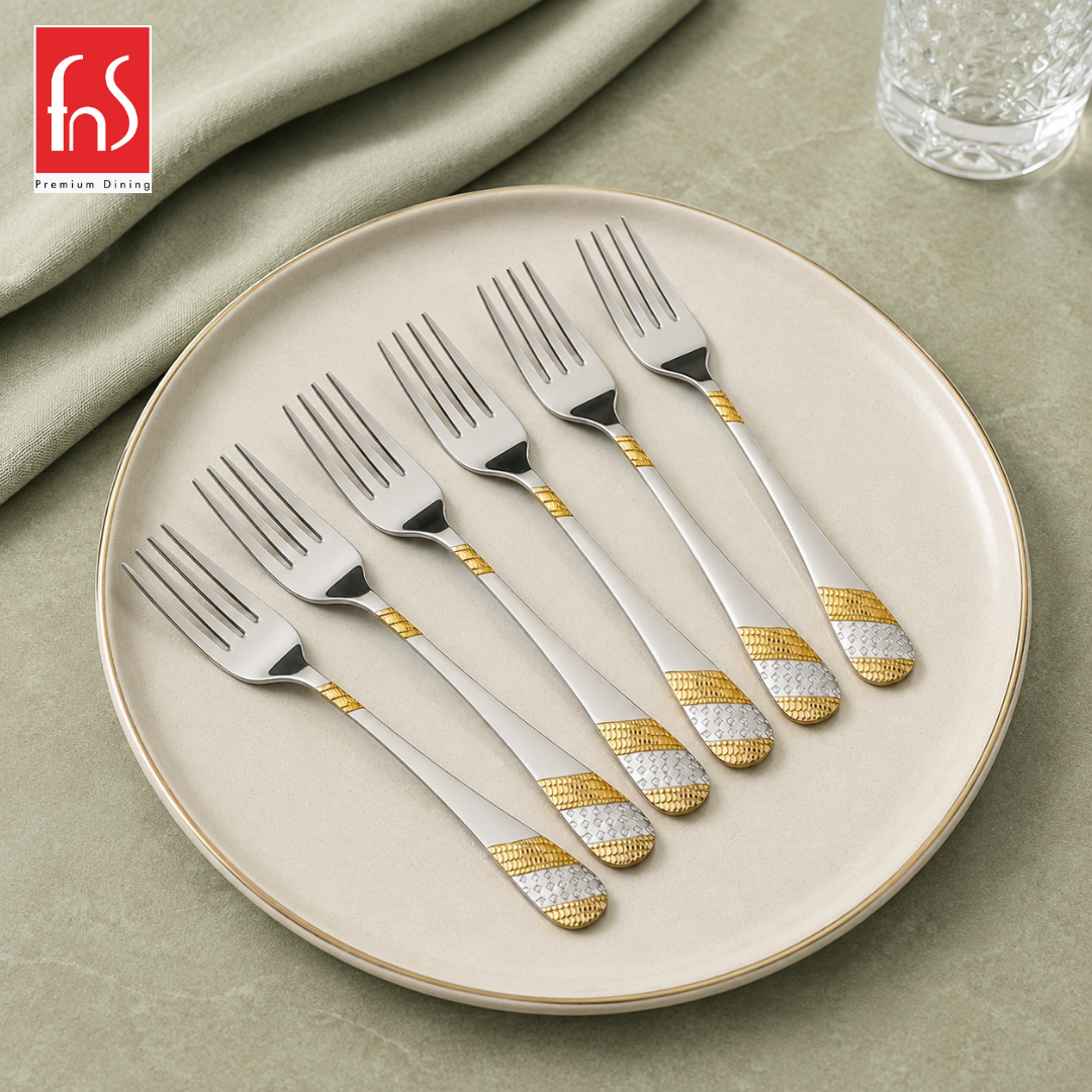 FnS Imperio Fruit Fork set of 6 pcs with silver and gold patterned handles, arranged diagonally on a round cream plate.