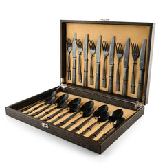 Luxury black cutlery set with patterned handles neatly arranged in an open presentation box with gold lining.