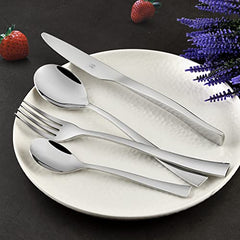 Sleek silver cutlery set neatly placed on textured plate with strawberries and purple flowers around.