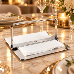 FnS Rico stainless steel napkin holder with center bar arms, polished finish and white napkins on a dining table and looking premium.