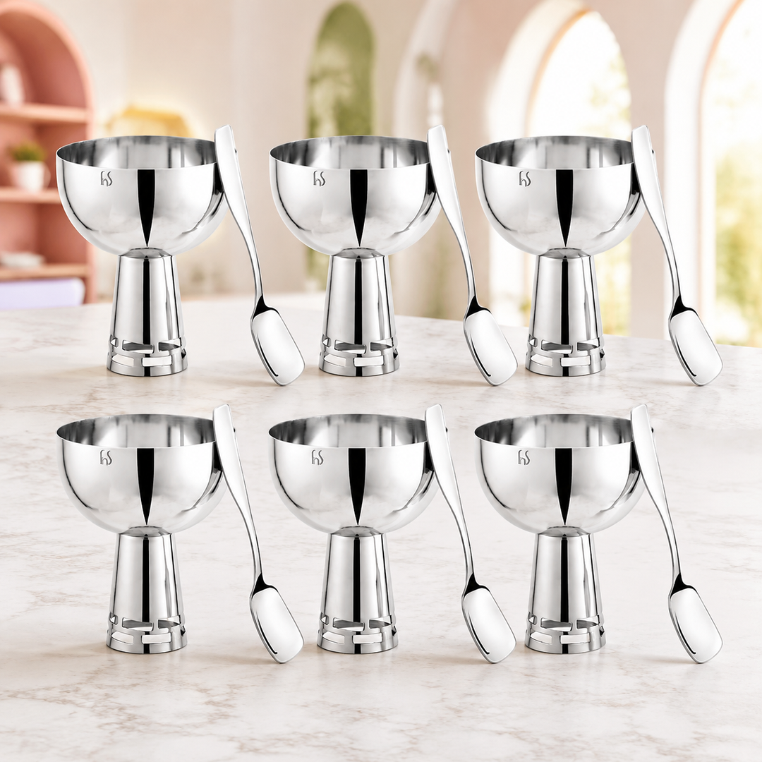 Alt Text: FnS Basil Stainless Steel Bowls Set of 6 in silver finish with six pedestal bowls and matching spoons on a marble table.