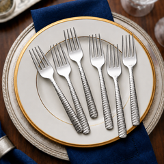 FnS Madrid 6-Pc Stainless Steel Dinner Fork Set with hammered handles arranged on a gold-rimmed plate with navy napkins.