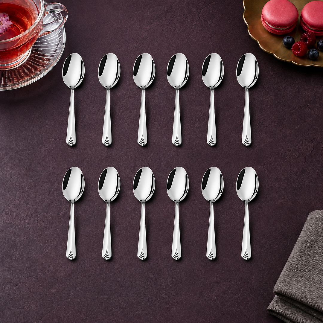 Montavo by FnS Divine 12-piece stainless steel tea spoon set arranged with rose tea, macarons and berries on a plum table.