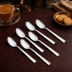 Montavo by FnS Helios 6-piece stainless steel tea spoon set with textured handles arranged beside masala tea and biscuits.