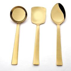 Top view of Alexa gold serving utensils showing gravy ladle, rice server, and large serving spoon in mirror finish