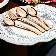Rose gold flatware neatly arranged on a decorative ceramic plate, surrounded by colorful table settings.