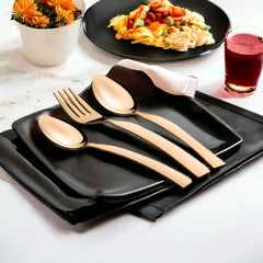 Elegant rose gold cutlery placed on black square plate with napkin, near pasta and flowers.