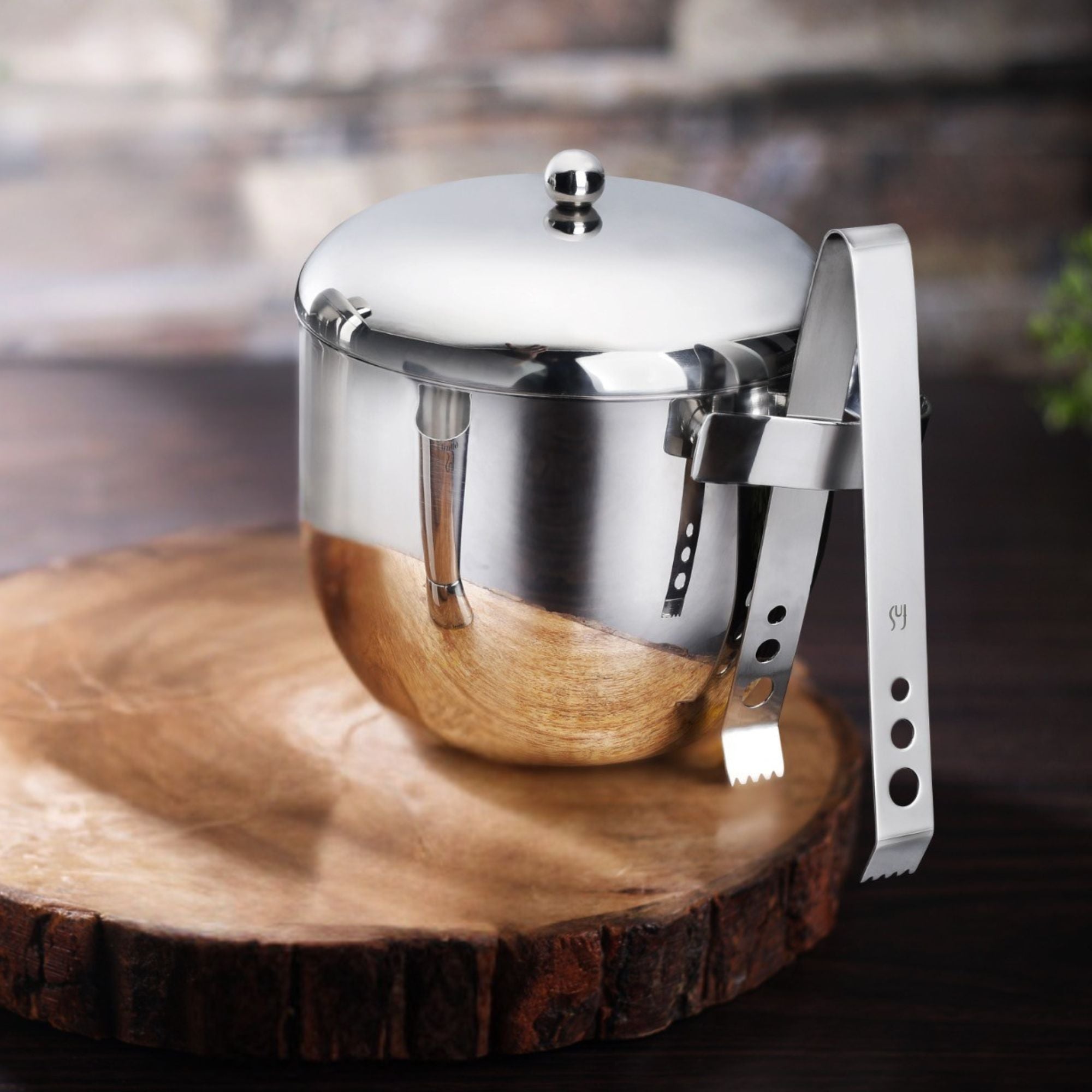 Apple ice bucket with transparent inner wall on wooden slice base with stainless steel ice tongs in lifestyle bar setting