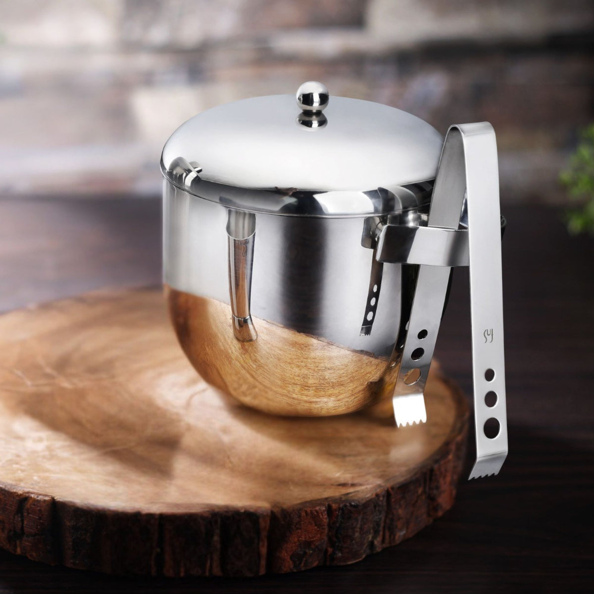 Apple ice bucket with transparent inner wall on wooden slice base with stainless steel ice tongs in lifestyle bar setting