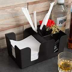 Black bar caddy organizer with multiple compartments holding white napkins, red and black straws, gold stirrers on counter with rum bottle and whiskey glass