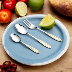 Stylish silver cutlery with gold accents arranged on a blue ceramic plate surrounded by fresh fruit.
