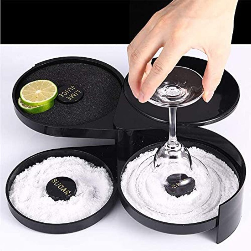 Black cocktail rimmer station with three compartments filled with salt and sugar, hand placing martini glass, fresh lime wedge on top