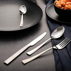 Knife, fork, and spoon placed elegantly beside black plate and bowl of roasted chickpeas.
