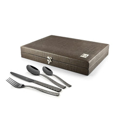 Patterned black cutlery set displayed beside a textured brown storage box with latch and metallic logo.