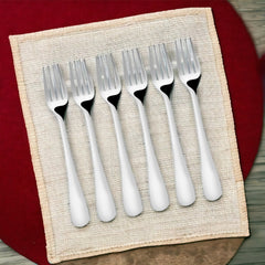 Six dinner forks displayed on woven placemat with red background