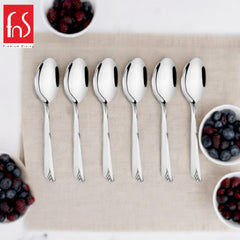 Six FNS Divine stainless steel dinner spoons displayed on beige linen with fresh berries in white bowls, premium dining setup